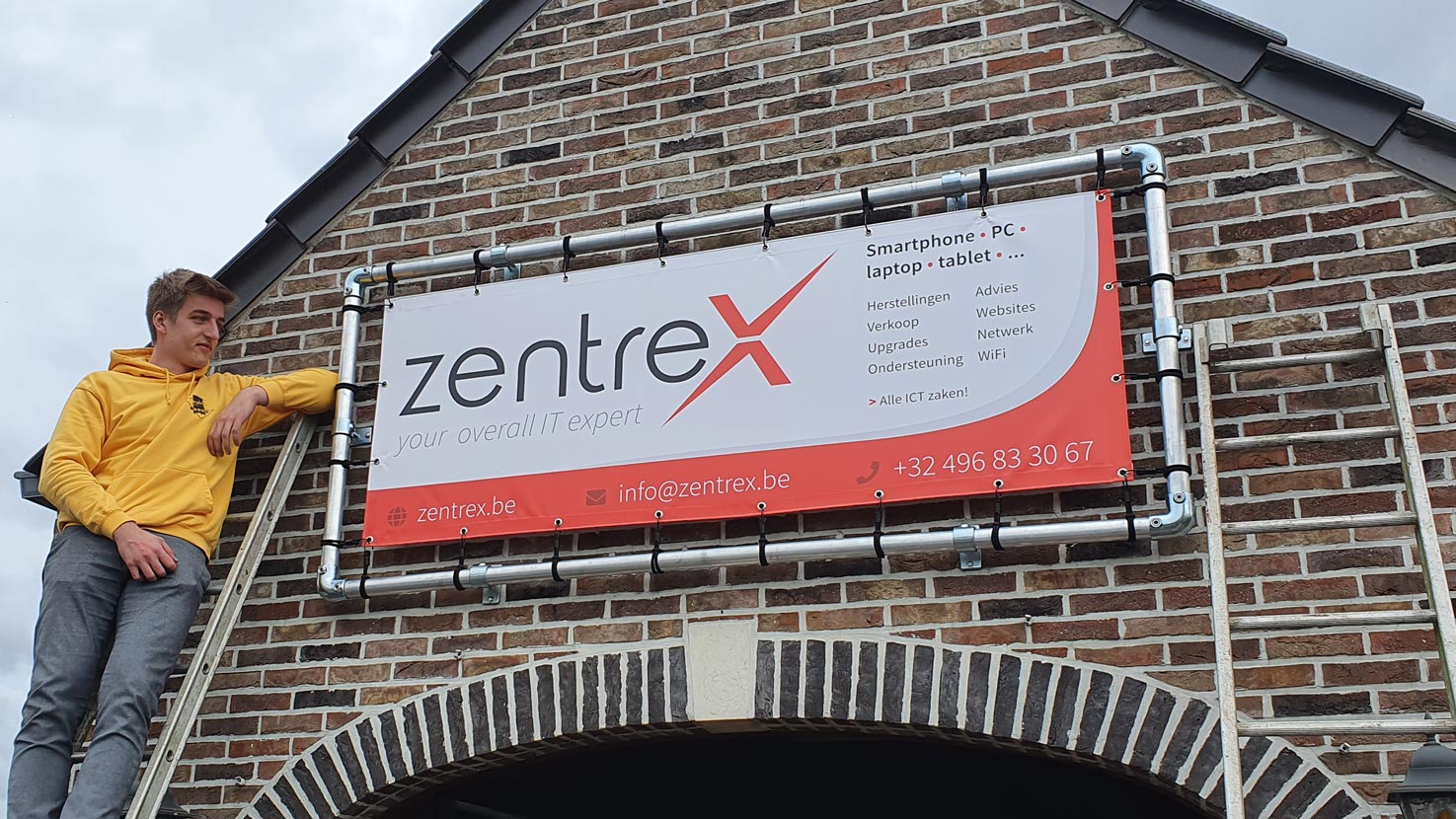 Printed Zentrex bannner hung up on the front of a house, with the owner next to it on a ladder